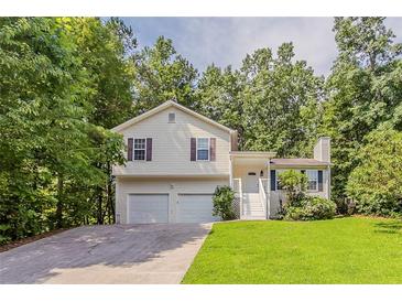 Charming split-level home featuring a two-car garage, and manicured lawn surrounded by mature trees at 441 Amy Blvd, Temple, GA 30179