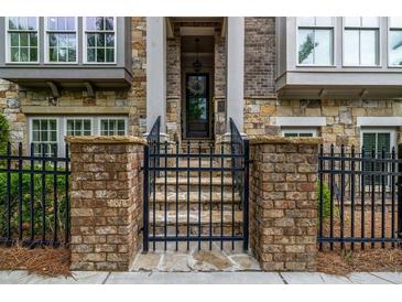 Charming brick and stone home entrance with landscaped steps, black iron fence and trimmed front door at 1120 Cordia Nw Ave, Atlanta, GA 30318