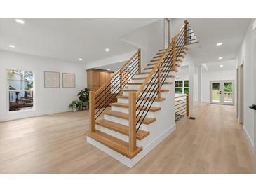 Bright, open staircase featuring wood treads, black metal railings, and plenty of natural light at 5150 Shadow Path Sw Ln, Lilburn, GA 30047