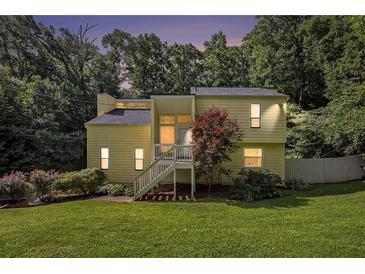 Two-story home with a well-manicured lawn and charming staircase entry nestled amongst mature trees at 1202 Laurel Cliff Se Dr, Smyrna, GA 30082