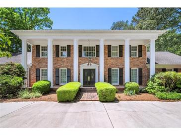 Stately brick home with white columns, black shutters, and manicured landscaping at 7590 Chaparral Dr, Atlanta, GA 30350