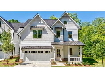Charming two-story home with white siding, a well-manicured lawn, and an attached garage with metal awnings at 136 Beutell St, Norcross, GA 30071