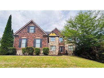 Traditional brick home featuring manicured lawn, stone accents and mature landscaping at 3784 The Great Dr, Atlanta, GA 30349