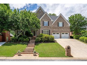 Charming two-story brick home featuring a well-manicured lawn, mature trees, and a two-car garage at 5589 Forkwood Nw Dr, Acworth, GA 30101