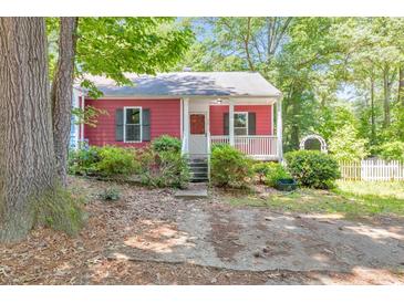 Charming single-story home with a red exterior, inviting front porch, and lovely landscaped front yard at 350 Pleasant Oak Sw Ct, Marietta, GA 30008