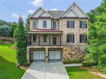 Charming two-story brick home with a stone foundation, a covered porch, and a two-car garage at 3394 Bryerstone Se Cir, Smyrna, GA 30080
