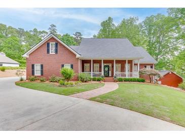 Charming brick home featuring a welcoming front porch, manicured lawn and mature trees at 4355 Old Hamilton Mill Rd, Buford, GA 30518