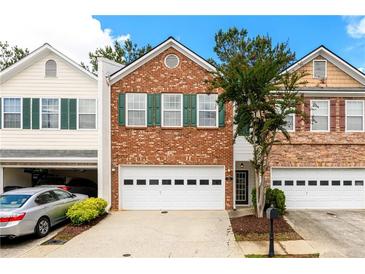 Two story brick townhome with a white garage door and manicured landscaping at 559 Woodland Park Ter, Lawrenceville, GA 30043