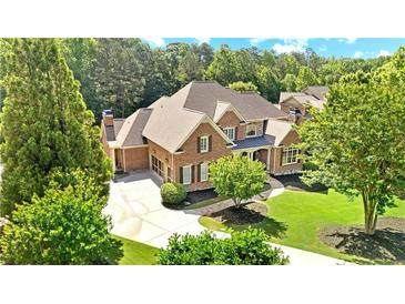 Stately brick home featuring a lush green lawn, mature trees, and an inviting circular driveway at 13037 Overlook Pass, Roswell, GA 30075