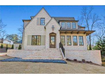 Charming two-story brick home with a well-manicured lawn, a covered porch, and elegant architectural details at 375 Chattahoochee St, Roswell, GA 30075