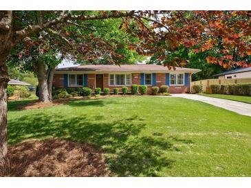 Charming brick home with a well-manicured lawn, blue shutters, and mature trees for shade at 3060 Wilson Rd, Decatur, GA 30033