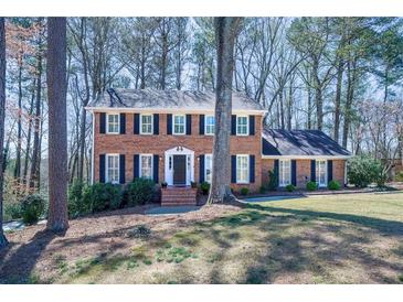 Charming two-story brick home with black shutters, and a well-manicured lawn in a serene, wooded setting at 725 Glengary Ne Way, Atlanta, GA 30342