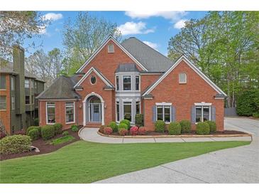 Charming brick home featuring lush landscaping, a well-manicured lawn, and a welcoming entrance at 1025 Saint Marks Walk, Suwanee, GA 30024