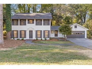 Charming two-story home features a well-manicured lawn, fresh paint, shutters, and an attached two-car garage at 4045 White Oak Sw Ln, Lilburn, GA 30047