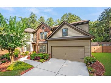 Charming two-story home featuring brick and tan siding, with a well-manicured lawn and two car garage at 1736 Dylan Pl, Lawrenceville, GA 30043