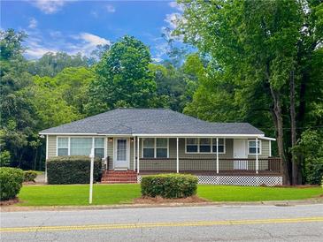 Charming single-story home featuring a welcoming front porch and lush green landscaping, perfect for serene living at 2790 Sardis Nw St, Kennesaw, GA 30144
