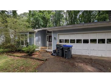 Quaint single Gathering home featuring a two-car garage and light blue vinyl siding at 345 Deerwood Dr, Suwanee, GA 30024