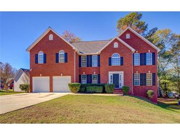 Traditional two-story brick home with a two-car garage and well-maintained lawn on a sunny day at 3071 Springfair Trott, Lithonia, GA 30038