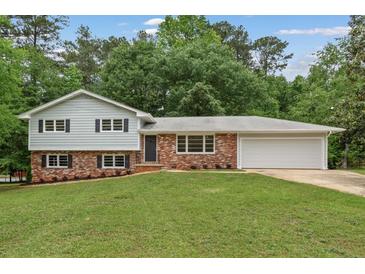 Charming split-level home featuring a brick facade, gray siding, and a well-manicured lawn at 3918 Oberlin Ct, Tucker, GA 30084