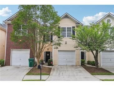 Charming two-story townhome featuring a one-car garage, well-maintained lawn, and mature landscaping at 7077 Biltmore Trce, Lithonia, GA 30058