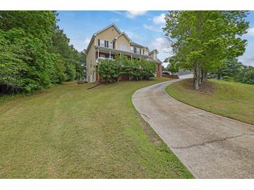 Inviting two-story home featuring a charming front porch and well-manicured lawn and a long driveway at 2530 River Run Dr, Dacula, GA 30019