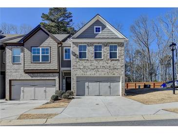 Charming townhome featuring a gray brick facade, two-car garage and inviting curb appeal at 2132 Arnage Dr, Lithonia, GA 30058