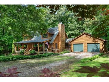 Charming log home with a two-car garage nestled in a wooded setting and featuring a welcoming front porch at 6605 Old White Mill Rd, Fairburn, GA 30213
