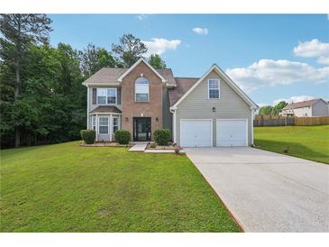Charming two-story home featuring a brick facade, two-car garage, and a lush green lawn at 701 Fir Chase, Fairburn, GA 30213