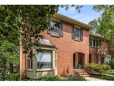 Charming brick townhome with an arched entryway, manicured landscaping, and window shutters at 1341 Sheffield Glen Ne Way, Atlanta, GA 30329