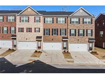 Row of townhomes with brick facades, driveways, and individual single-car garages at 3075 Westpoint Cir, Snellville, GA 30078