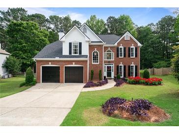 Charming brick two-story home with a two-car garage and a beautifully landscaped front yard at 523 Huntgate Rd, Woodstock, GA 30189