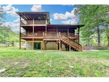 Exterior log home showcasing a multi-level deck and walkout basement on a lush green lawn at 2864 Winder Hwy, Dacula, GA 30019