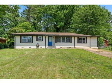 Charming single-story home with well-maintained lawn, painted white brick, contrasting trim and a blue front door at 1824 Atherton Dr, Decatur, GA 30035