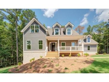 Charming two-story home with a welcoming front porch and well-manicured lawn in a wooded setting at 220 Nicklaus Cir, Social Circle, GA 30025