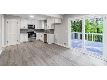 Bright, newly renovated kitchen with stainless steel appliances and white cabinets with access to an outdoor deck at 5857 Earlwane Dr, Lithonia, GA 30058