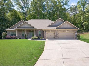 Charming brick home boasts a manicured lawn and a spacious driveway leading to a two-car garage at 150 Whitworth Dr, Locust Grove, GA 30248