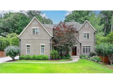 Beautiful brick home featuring a manicured lawn, mature trees, and professional landscaping at 272 Lake Forrest Ne Ln, Atlanta, GA 30342