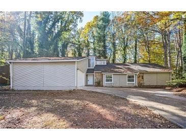 Inviting single-story home featuring stone accents and a large, private front yard surrounded by mature trees at 5474 Post Road Pass, Stone Mountain, GA 30088