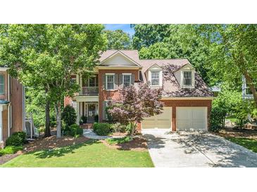 Charming two-story brick home with attached two-car garage and manicured front lawn at 1600 Heritage Trl, Roswell, GA 30075
