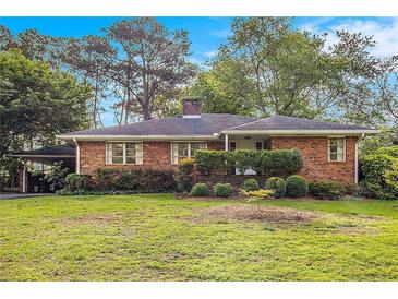 Charming single-story brick home featuring a well-manicured lawn and mature trees in a serene setting at 894 Nottingham Dr, Avondale Estates, GA 30002