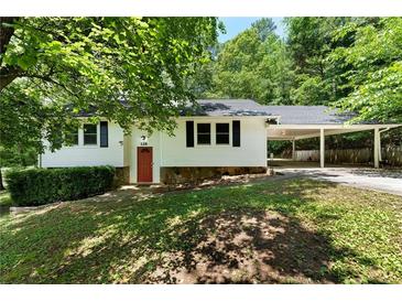 Charming single-story home with a red front door, carport, and lush greenery at 128 Reynolds Bridge Rd, Kingston, GA 30145