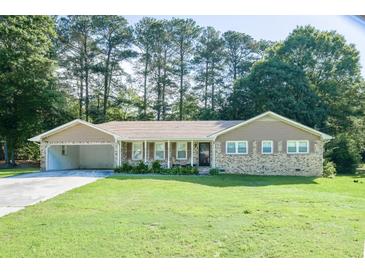 Charming brick ranch-style home with an attached carport and a well-maintained front lawn at 2628 Hickory Trl, Snellville, GA 30078