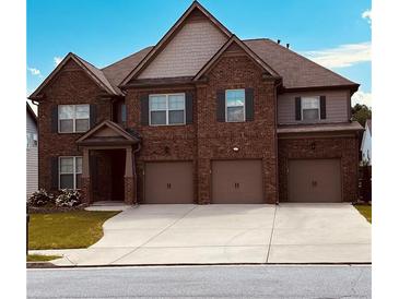 Charming two-story brick home featuring a three-car garage and well-manicured lawn against a bright blue sky at 419 Woodmill Way, Atlanta, GA 30331