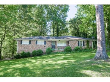 Charming single-story brick home nestled among mature trees and a lush, green lawn at 4236 Beaver Ruin Nw Ct, Lilburn, GA 30047