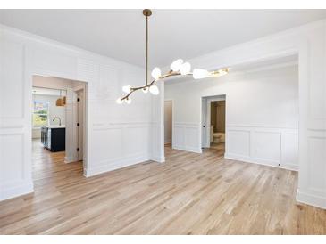Bright dining room with white wainscoting, hardwood floors and unique lighting fixture at 4377 Hosch Reserve Dr, Buford, GA 30519