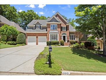 Charming brick two-story home with a well-manicured lawn, two-car garage and a classic architectural style at 580 Washington Way, Cumming, GA 30040