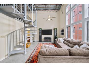 Bright living room featuring a spiral staircase, high ceilings, large windows, and a comfortable sofa at 572 Edgewood Se Ave # 303, Atlanta, GA 30312