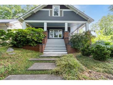 Charming gray two-story home with a covered front porch, white trim and lush green landscaping at 1228 Hosea L Williams Ne Dr, Atlanta, GA 30317