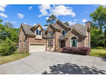 Beautiful brick home with a well-manicured lawn and a spacious driveway, featuring a two-car garage and a welcoming entrance at 1614 Rucker Rd, Alpharetta, GA 30009