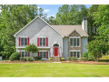 Charming two-story home with a well-manicured lawn, stone accents, red shutters and a bright red front door at 4638 Arrow Wind Dr, Powder Springs, GA 30127